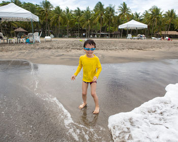 Boy laughing while standing on shore