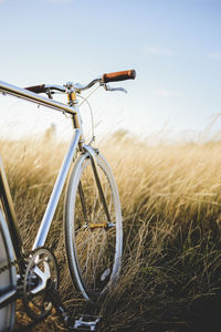 Bicycle on golden field against sky during sunset