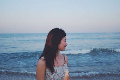 Woman standing at beach against sky