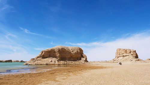 Rock formations on beach against blue sky