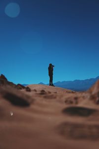 Person standing on sand with sky in background