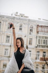 Woman having red wine while wrapped in blanket at balcony