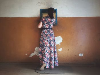 Rear view of woman standing against wall