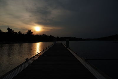 Pier over lake against sky during sunset