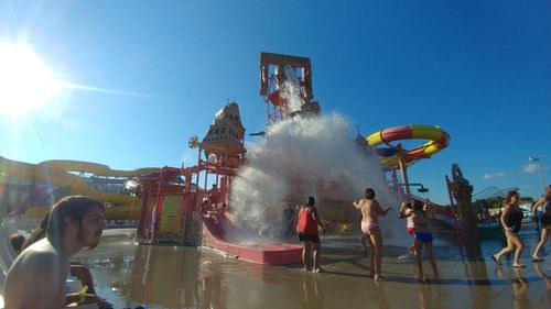 People by swimming pool against clear sky