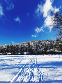Snow covered field against blue sky