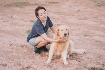 Woman with dog crouching on land