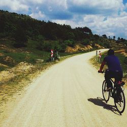 People riding bicycle on road against sky