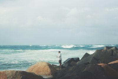 Side view of man on rock fishing in sea