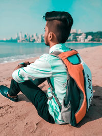 Rear view of man sitting on beach