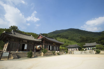 Houses by trees and buildings against sky