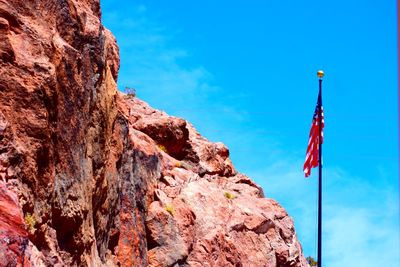 Low angle view of red flag on mountain against sky