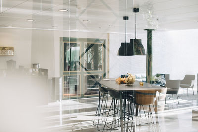 Tables and chairs arranged in lobby seen through glass at office