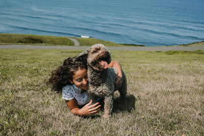 Smiling woman with dog lying on grassy land