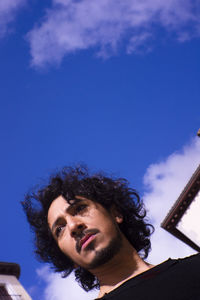 Low angle view of young man against blue sky