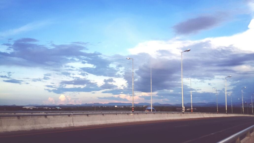 sky, transportation, cloud - sky, road, street light, road marking, the way forward, cloudy, street, cloud, car, mode of transport, lighting equipment, blue, outdoors, weather, nature, land vehicle, dusk, on the move