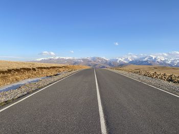 Road leading towards mountains against sky