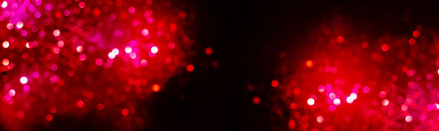 Defocused image of illuminated lights against black background