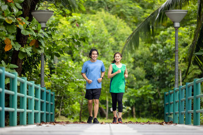 Full length of a smiling man and woman walking on plants