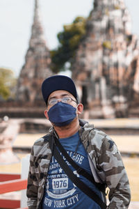 Portrait of young man looking away while standing outdoors