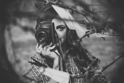 Portrait of woman photographing by branches