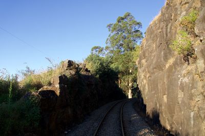 Road amidst rocks against clear blue sky