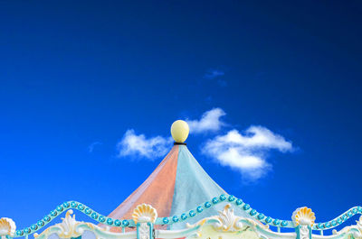 High section of carousel against blue sky