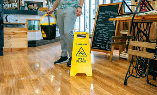 Worker placing wet floor sign after mopping the floor