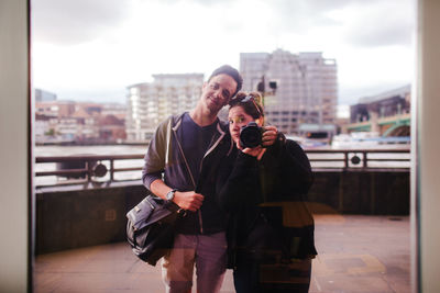 Full length of man photographing in city against sky