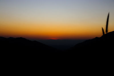 Scenic view of silhouette mountains against orange sky