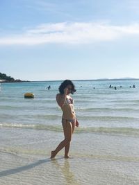 Full length of woman standing on beach against sky