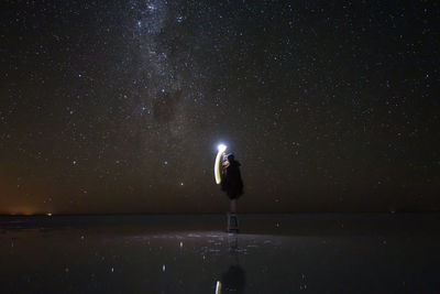 Man standing in illuminated field against sky at night