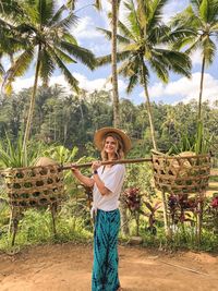 Woman standing by palm trees