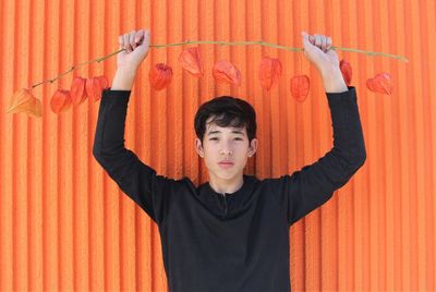 Portrait of teenage girl standing against orange wall