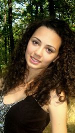 Portrait of smiling young woman against tree trunk