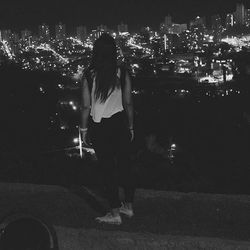 Rear view of woman standing on illuminated city at night