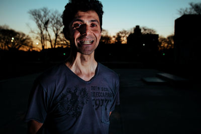 Portrait of man standing by road against sky during sunset