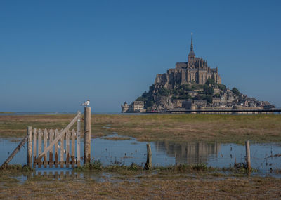 France's iconic mont st michel in the distance with an old gate and fence in the tidal foreground