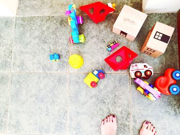 Cropped legs of woman standing by toys on floor