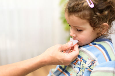 Cropped hand of mother taking saliva sample of girl