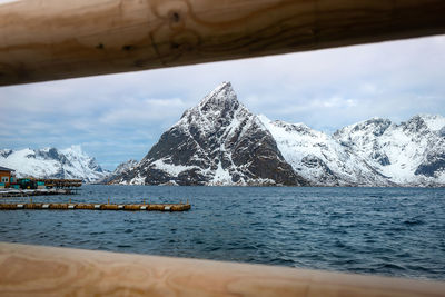 Scenic view of sea by snowcapped mountain against sky