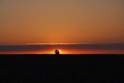 Silhouette of man couple standing on landscape at sunset