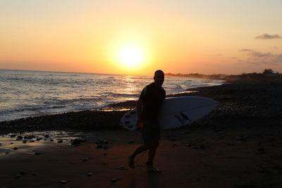 Man on beach against sky during sunset