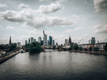 River by buildings in city against sky