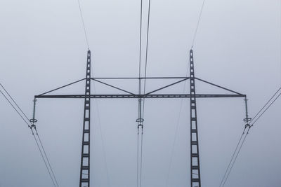 Low angle view of electricity pylon against clear sky