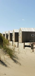 Beach huts by buildings against clear sky