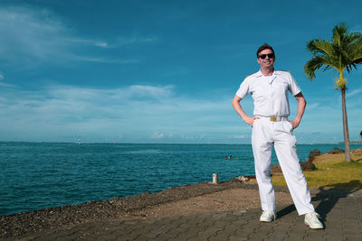 Portrait of young man standing in sea against sky