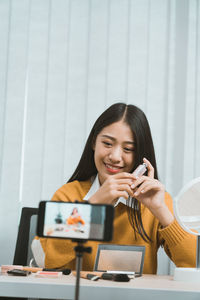 Young woman using mobile phone while sitting on table