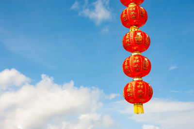 Low angle view of lanterns hanging against blue sky