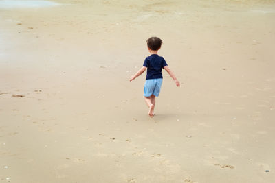 Rear view of boy running at beach